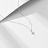 Silver cross pendant necklace with diamond pavé accents on fine link chain, photographed against geometric white background