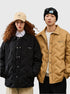 Two models standing against white background, woman wearing black quilted jacket with Brixton cap, man in tan quilted jacket with black beanie