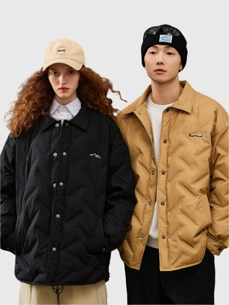 Two models standing against white background, woman wearing black quilted jacket with Brixton cap, man in tan quilted jacket with black beanie