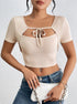 Front view of a woman in beige ribbed crop top holding a white clutch.