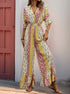  Woman in a wide-leg jumpsuit with a patchwork floral and geometric print, featuring a deep V-neck and cinched waist.