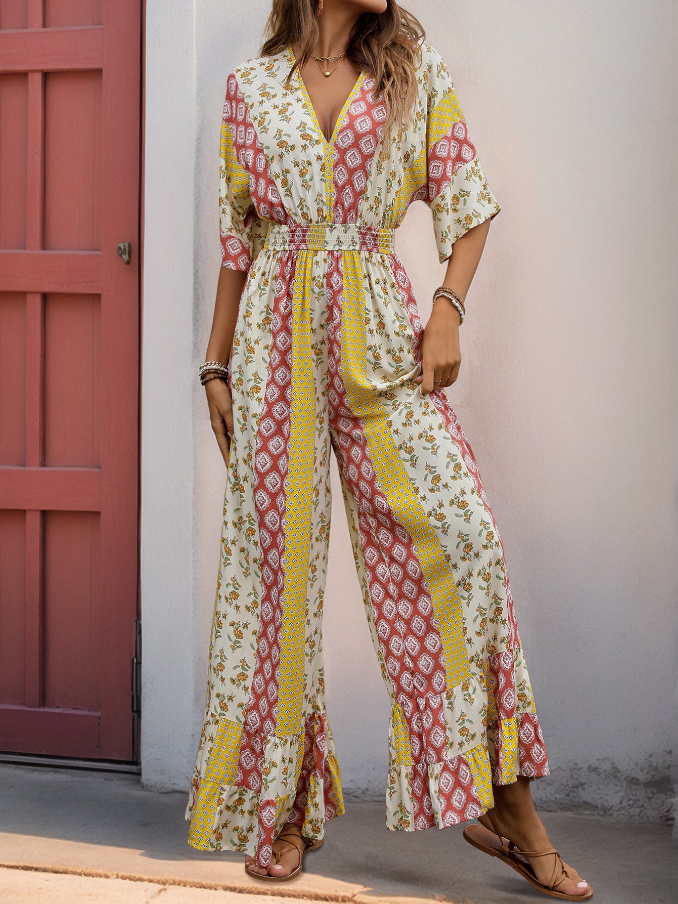  Woman in a wide-leg jumpsuit with a patchwork floral and geometric print, featuring a deep V-neck and cinched waist.