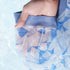 Close-up of blue geometric patterned underwear fabric being held in water, showing moisture-wicking technology