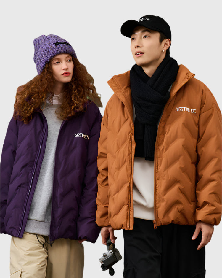 woman wearing purple quilted jacket with matching beanie and man in camel brown quilted jacket with black scarf and baseball cap