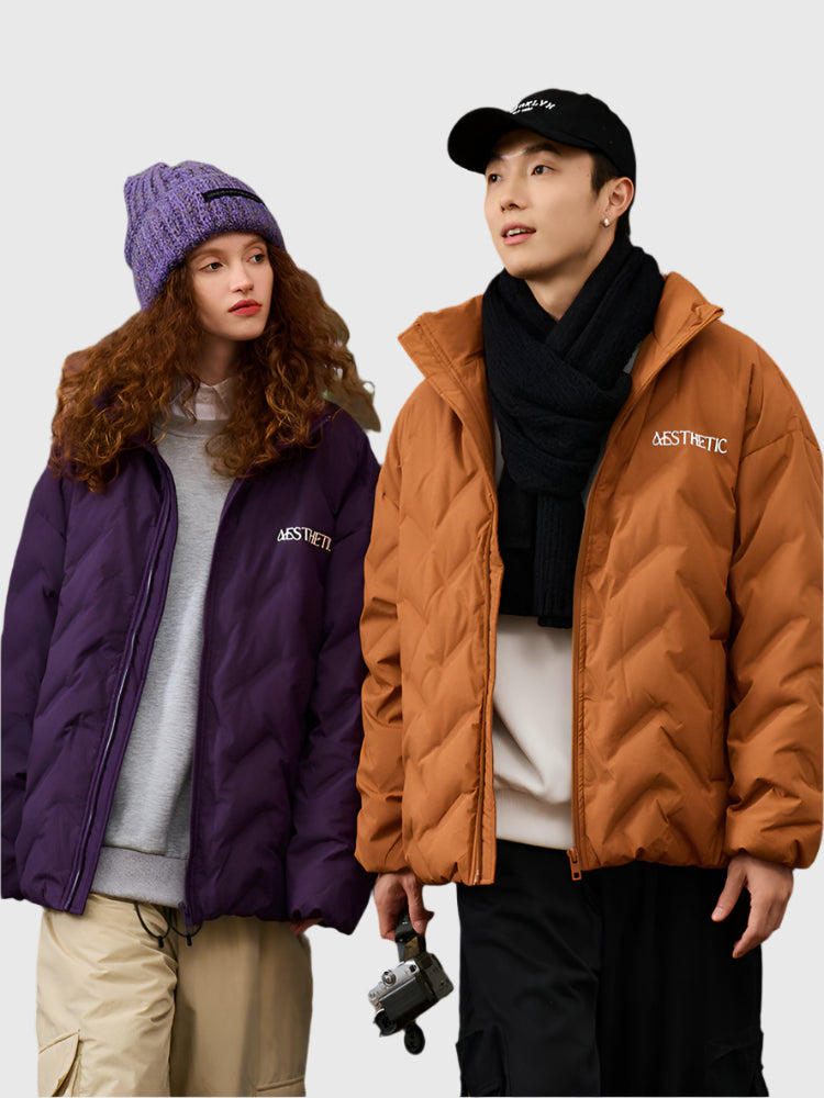 woman wearing purple quilted jacket with matching beanie and man in camel brown quilted jacket with black scarf and baseball cap