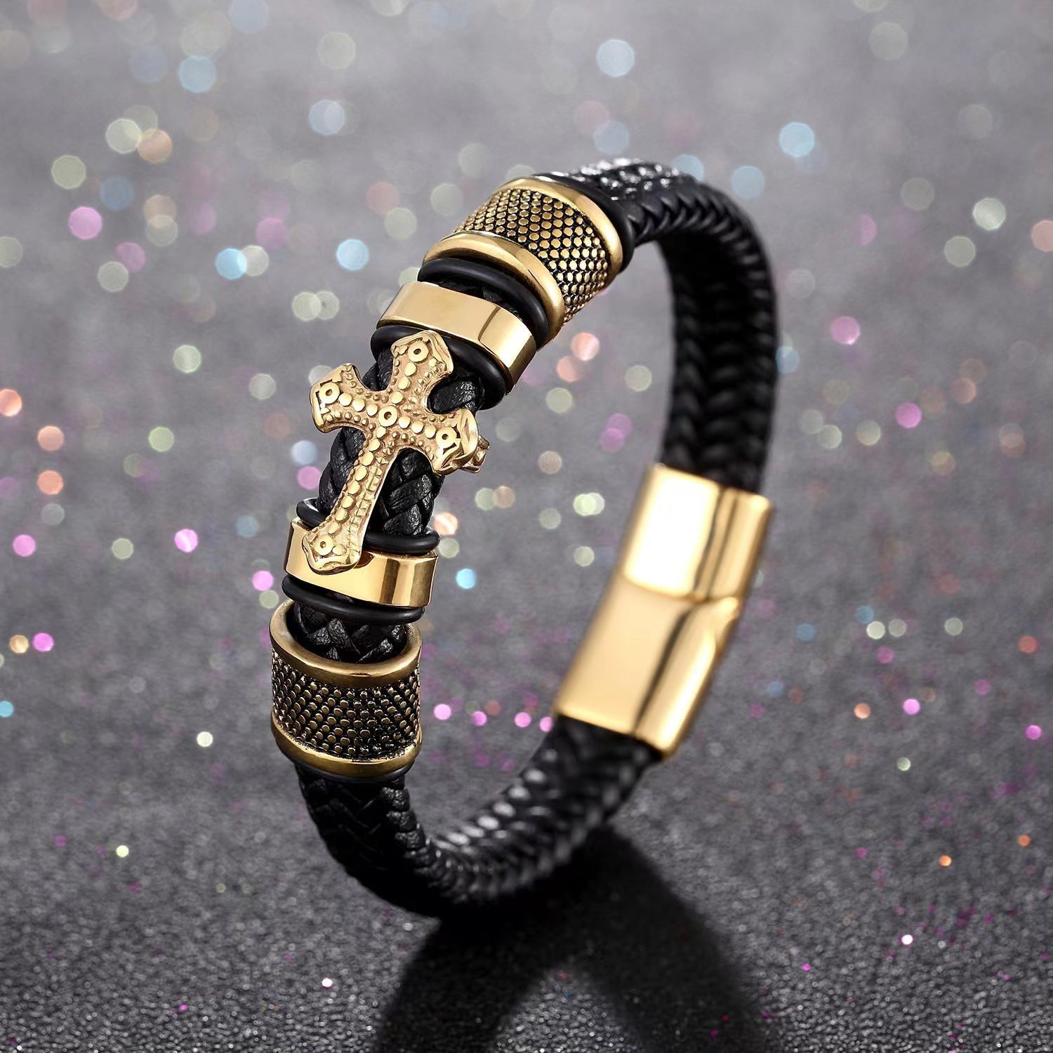 Gold-tone cross bracelet on black braided leather with metal accents and a magnetic clasp.