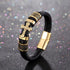 Gold-tone cross bracelet on black braided leather with metal accents and a magnetic clasp.