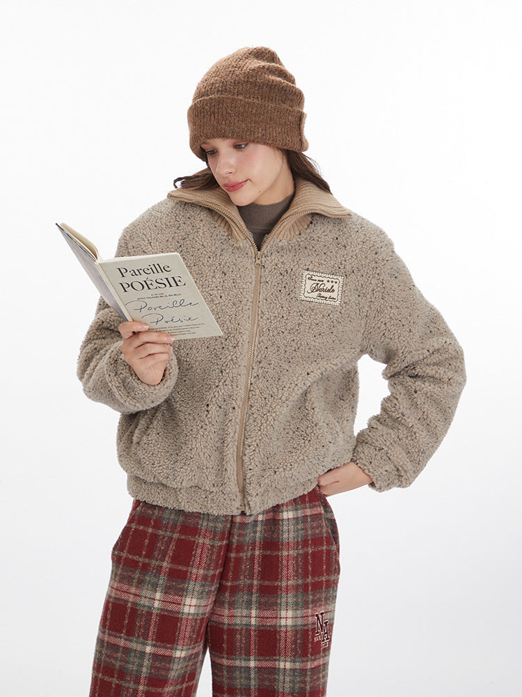 Model reading poetry book while wearing beige teddy fleece jacket with Marule patch, brown beanie and plaid pants on white background