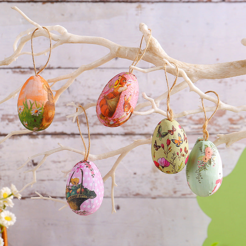 Hanging Easter egg ornaments with vintage rabbit and floral patterns, suspended on a white decorative tree branch.