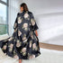 Back view of the black and beige floral satin long robe, displaying the full length and floral print with city buildings visible