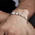 Men's stainless steel bracelet with white pearls and geometric links, worn on wrist. Elegant and modern design for everyday wear.
