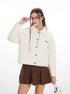 Woman wearing a white jacket with red buttons and a brown skirt on a white background
