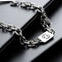 Stainless steel zodiac bracelet with a Cancer symbol charm, displayed on a black leather surface for a sleek, modern look.