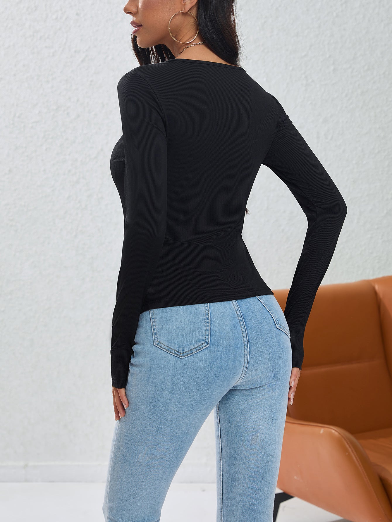 Back view of fitted black long sleeve top showing clean lines and form-fitting silhouette with jeans