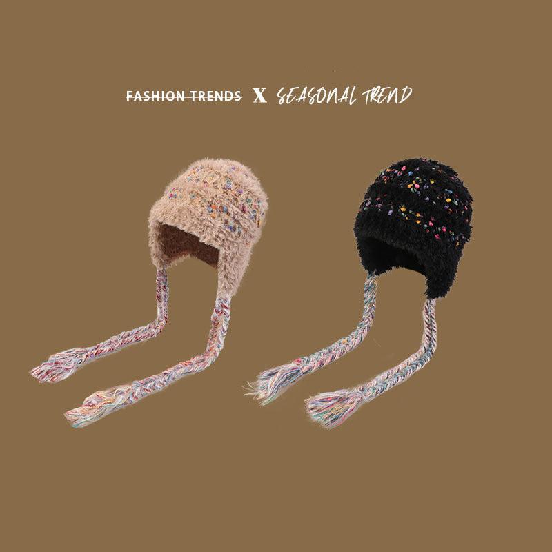 Earflap winter hats in beige and black with multicolored speckled design and braided ties, highlighting fashion and seasonal trends