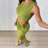 A close-up, angled selfie of a woman in a green ribbed crop top and matching high-waisted slit skirt, showcasing the fitted design and textured fabric.