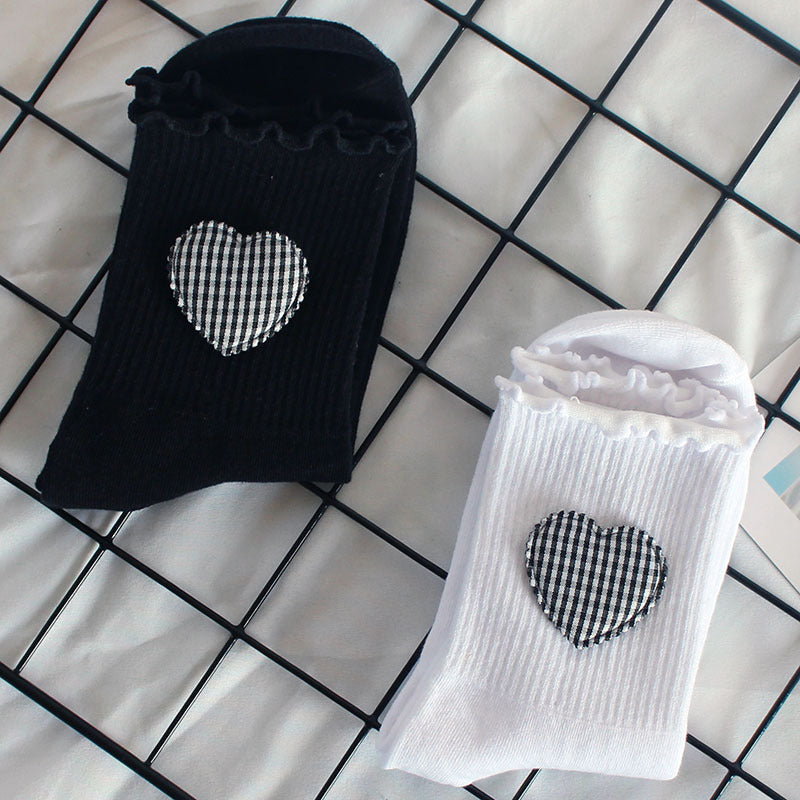 Black and white crew socks with ruffle trim and gingham heart patches, showing detailed pattern