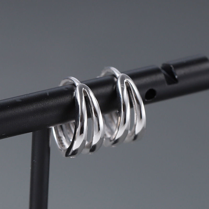 Double-band silver hoop earrings displayed on black jewelry stand
