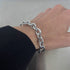 Close-up of a wrist wearing a chunky silver chain bracelet.
