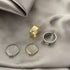 Four butterfly rings displayed on gray silk: wide bands and thin bands in gold and silver finishes