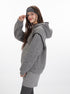 Side view of heather grey hoodie showing oversized fit, black contrast stitching details, and kangaroo pocket. Paired with grey cable knit shorts