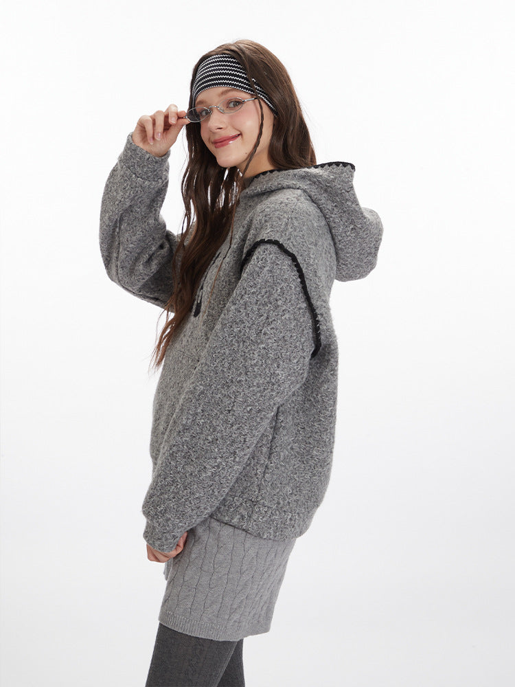 Side view of heather grey hoodie showing oversized fit, black contrast stitching details, and kangaroo pocket. Paired with grey cable knit shorts