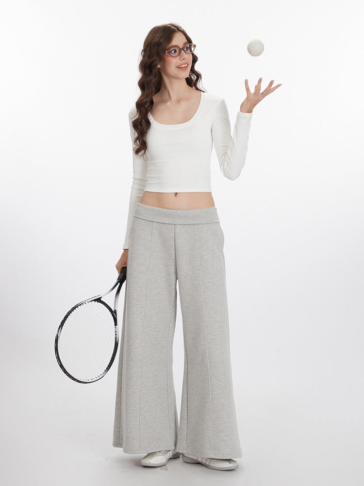 White long-sleeve crop top with scoop neckline shown with light gray wide-leg athletic pants, styled with tennis racket and ball