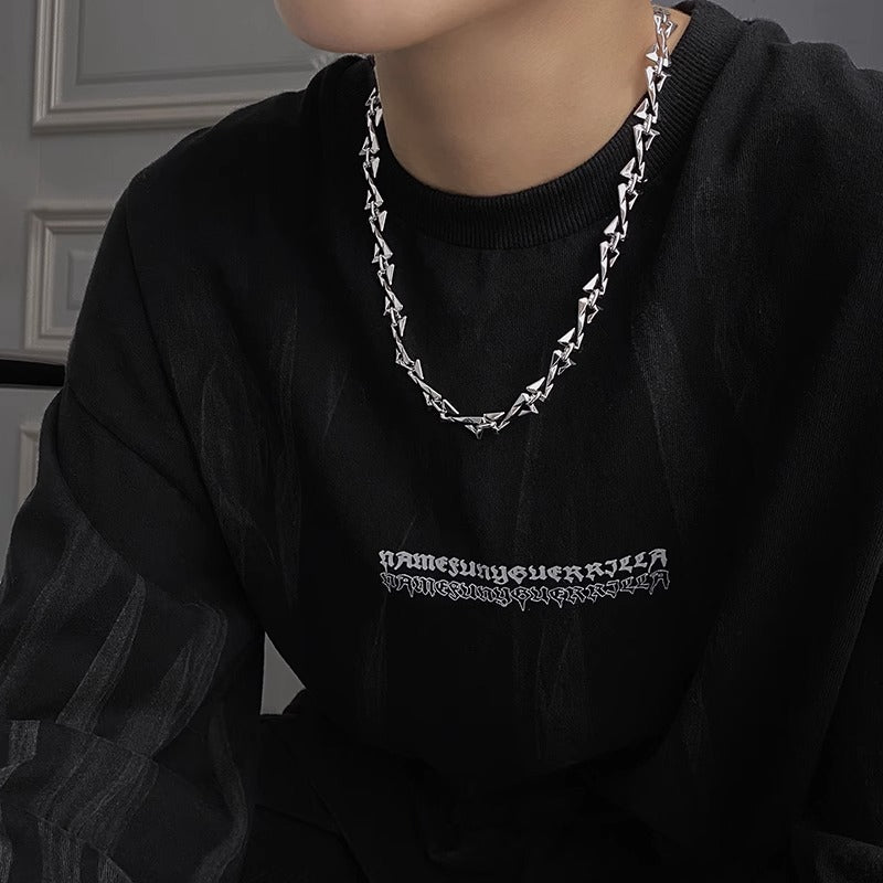 Silver geometric necklace worn with dark gray top