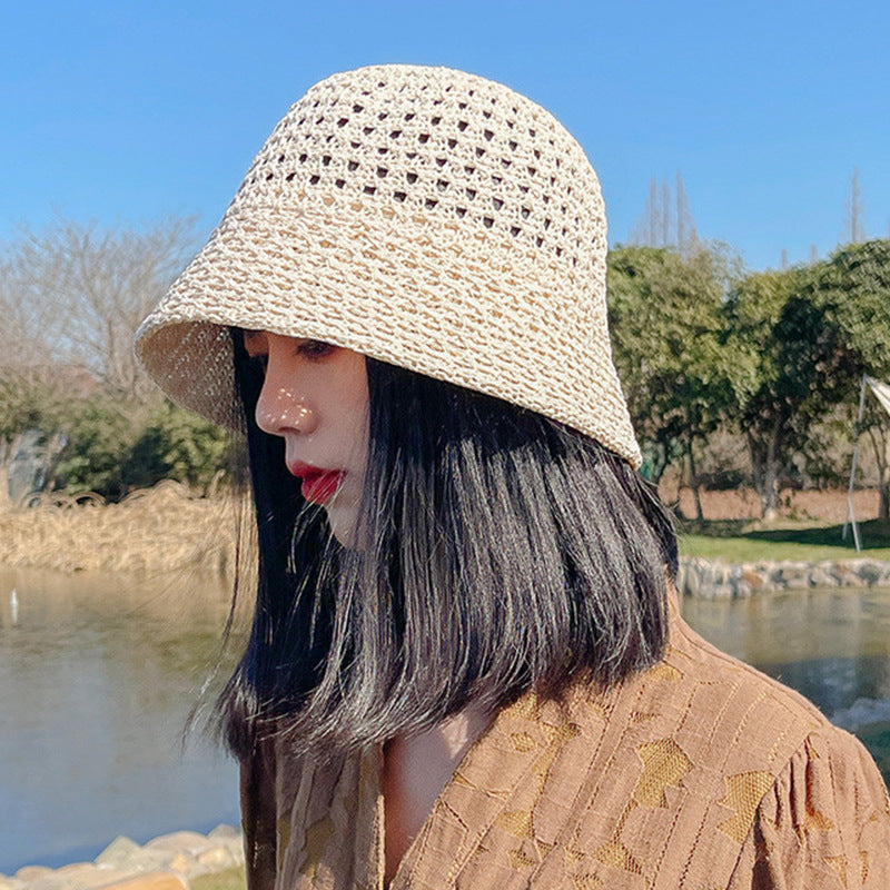 Side view of a woman wearing a beige straw bucket hat with breathable open-weave crochet design, standing near a lake with a natural background.
