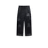 Black Backstairs sweatpants with wide-leg fit, elastic waistband with drawstring ties, distressed paint-effect pattern, and silver logo print