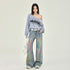 A model wearing an off-shoulder Raiders sweatshirt, wide-leg jeans with pastel tie-dye effect, white belt, and sneakers against white backdrop