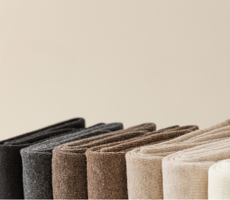 Row of knit leg warmers in neutral tones from black to cream