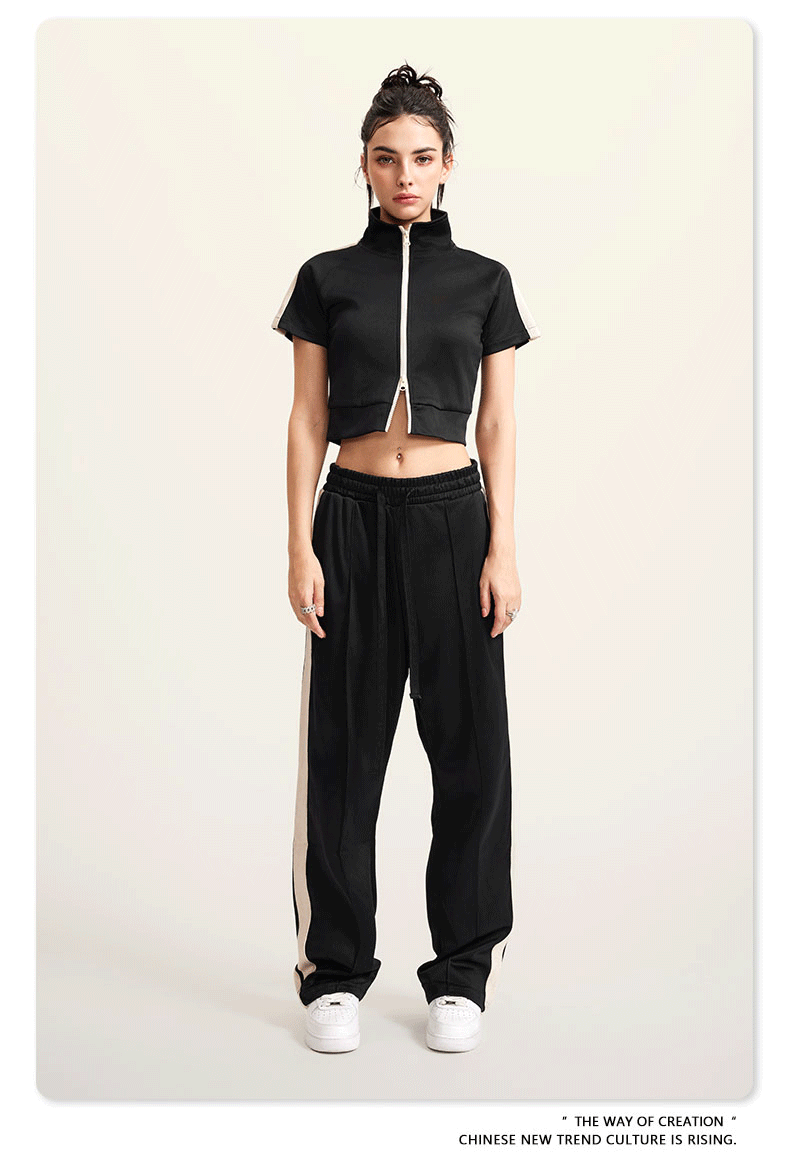 Woman in black cropped jacket and wide-leg pants, holding white bag