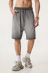A man wearing light gray washed cotton shorts with elastic waistband, gold watch and white athletic socks against white background