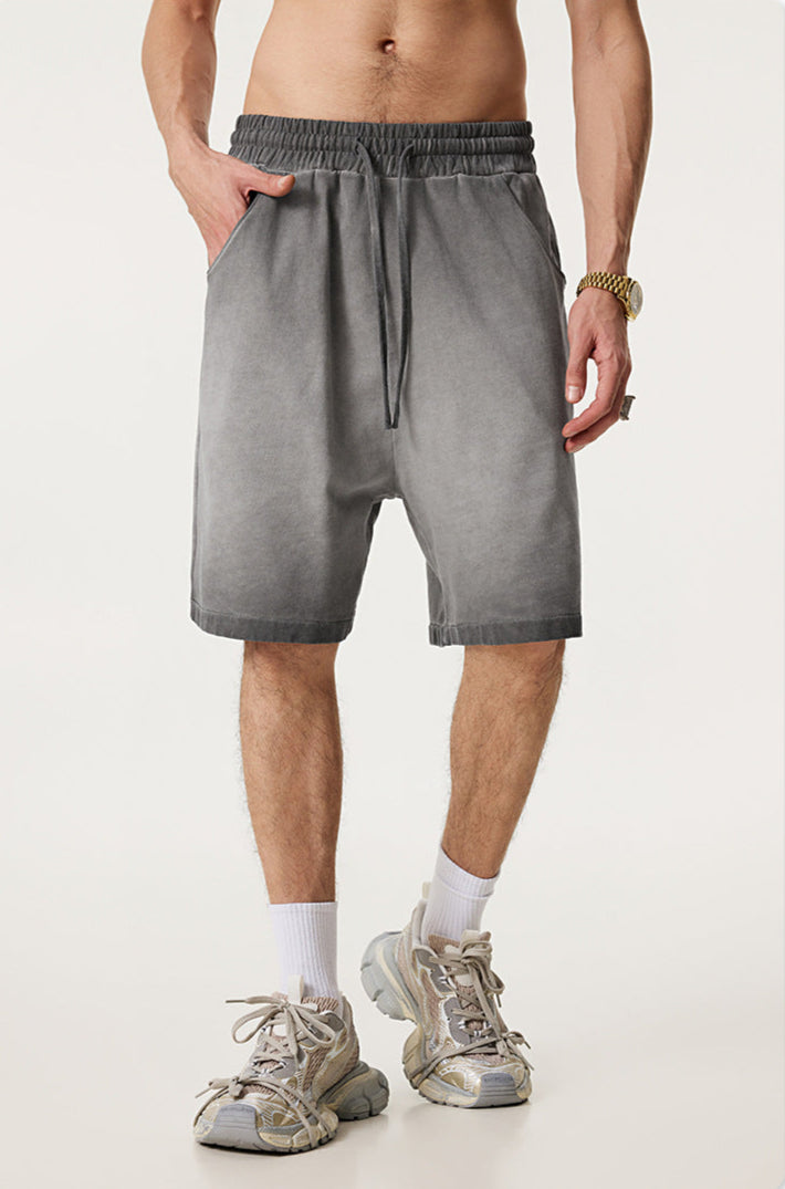 A man wearing light gray washed cotton shorts with elastic waistband, gold watch and white athletic socks against white background