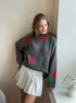 Gray oversized sweater with red rose pattern, paired with white pleated mini skirt, indoor fashion shot