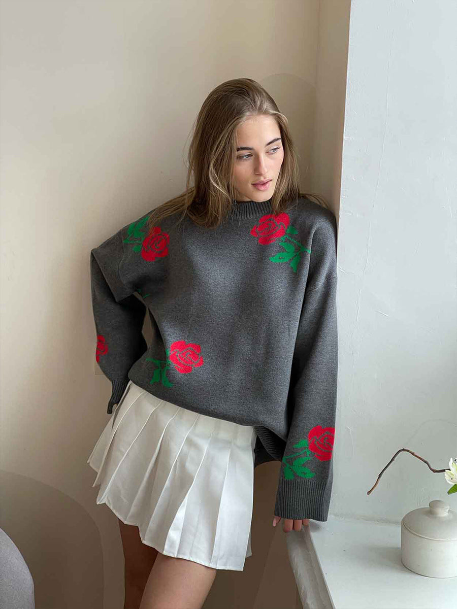 Gray oversized sweater with red rose pattern, paired with white pleated mini skirt, indoor fashion shot