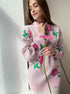Light pink sweater with rose pattern, model holding pink gerbera daisy in natural lighting