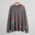 Gray crewneck sweater with scattered red rose and green leaf pattern on display hanger
