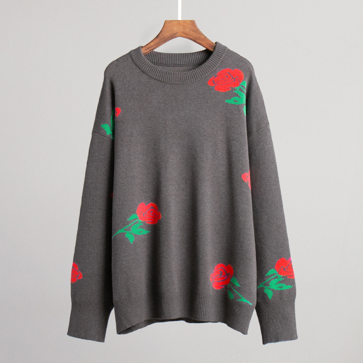 Gray crewneck sweater with scattered red rose and green leaf pattern on display hanger