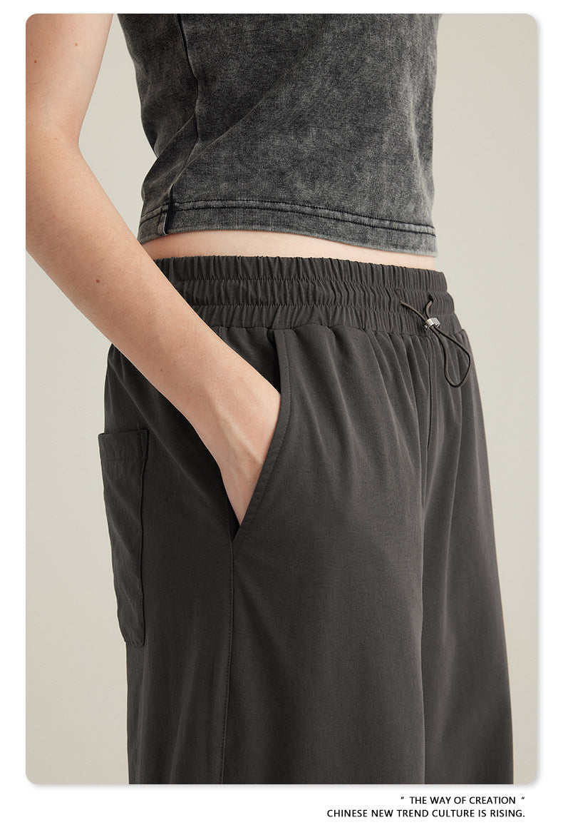 Detail shot of charcoal gray cargo pants elastic waistband and side pocket with washed black crop top