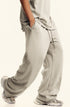 Side view of light beige sweatpants with pockets and textured pattern. Paired with matching top and designer footwear