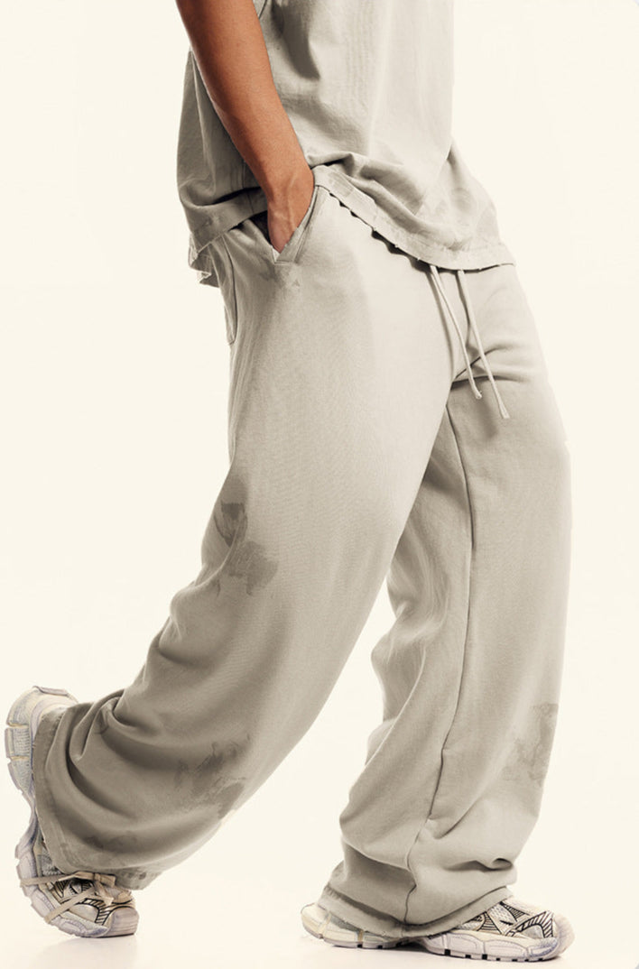 Side view of light beige sweatpants with pockets and textured pattern. Paired with matching top and designer footwear