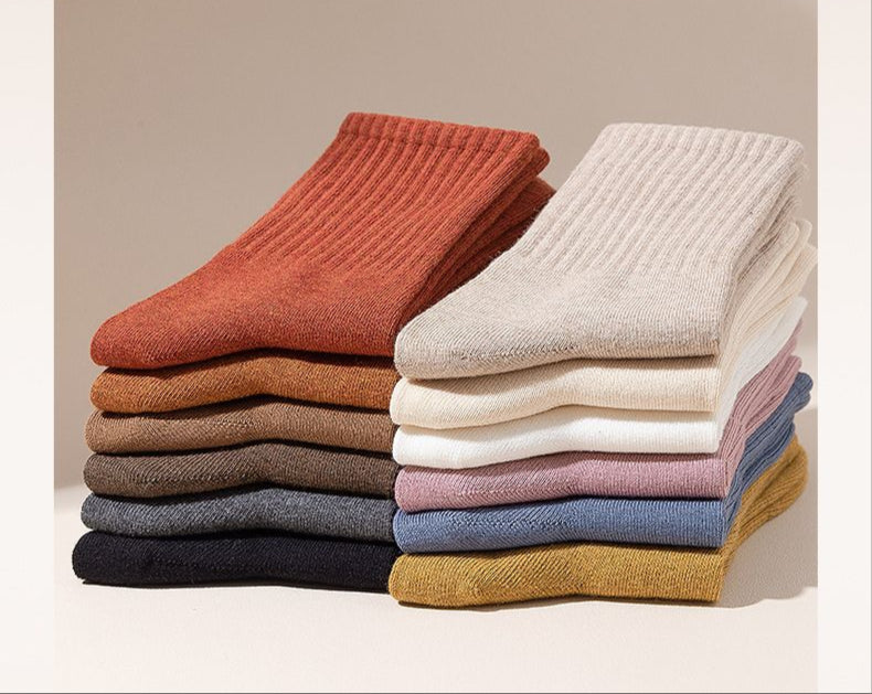 Stacked neutral-colored socks in sienna, beige, white and light gray against white background