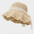 A beige straw sun hat with a ruffled brim and intricate lace detailing, complete with a romantic lace bow for a vintage touch.
