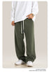 Person wearing white long-sleeve shirt and olive green sweatpants with white drawstring and side pockets
