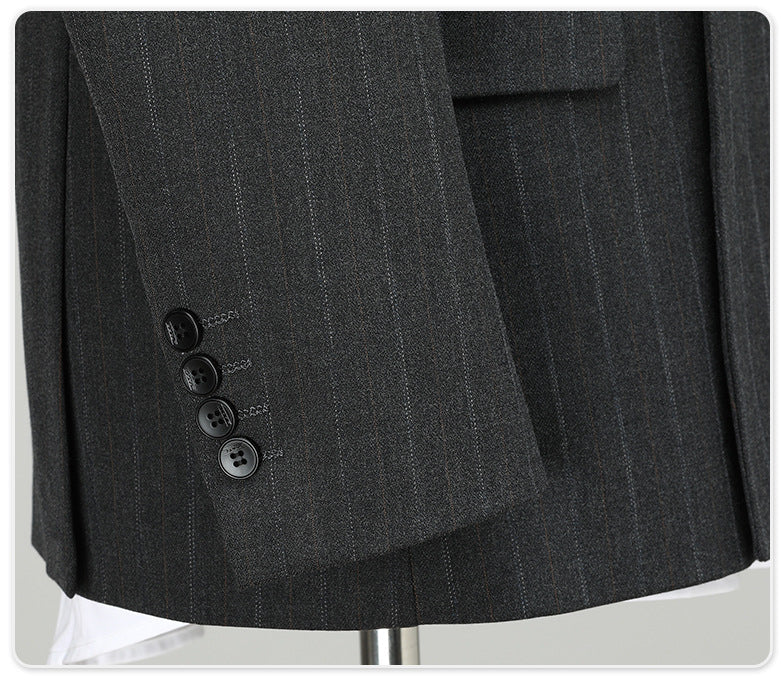 Close-up of jacket sleeve with four-button detail on charcoal pinstripe wool fabric