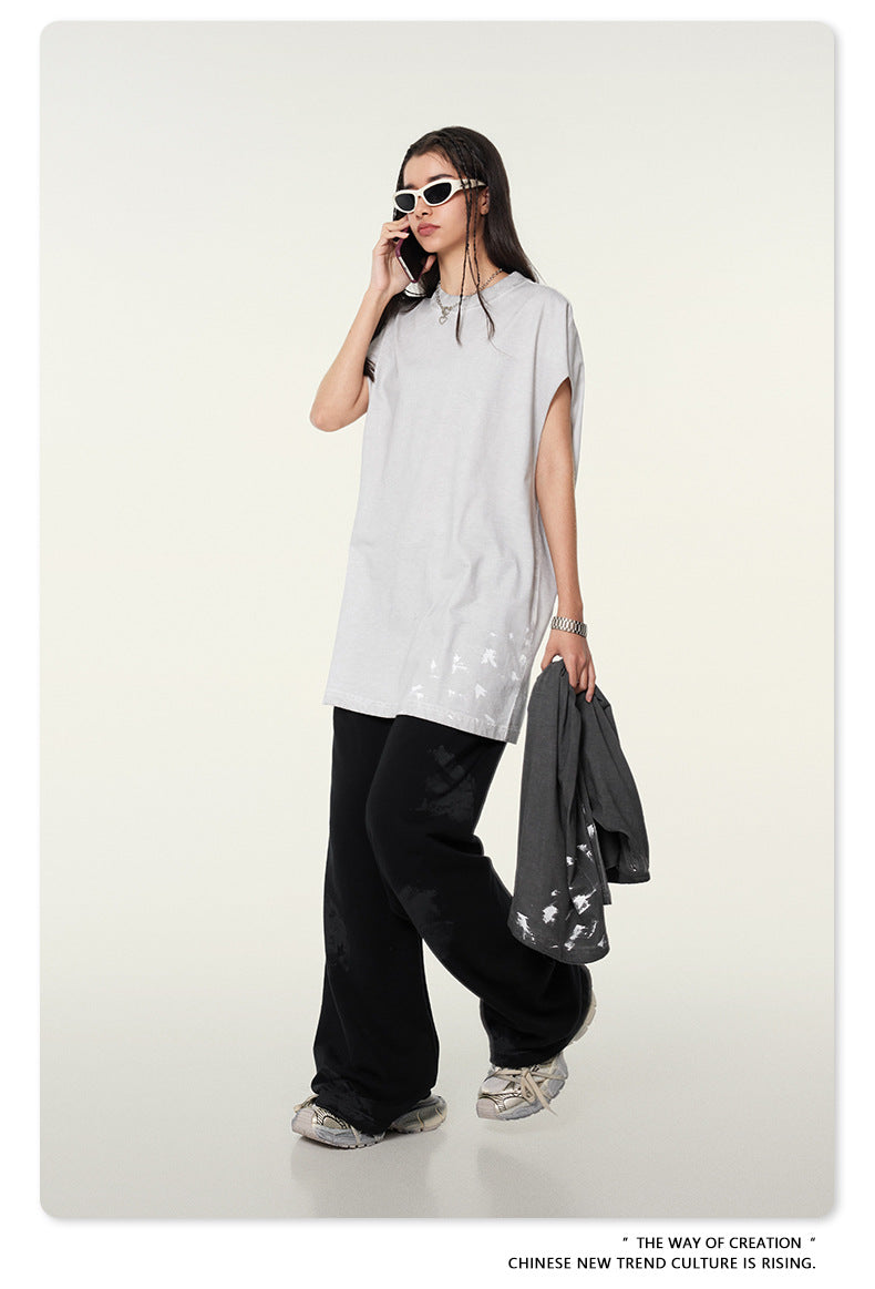 Model with dark hair wearing white t-shirt, black pants, white sunglasses, holding phone and gray jacket