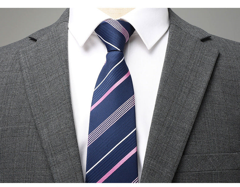 Close-up of navy and pink striped tie against white collar and gray suit lapels showing textured fabric detail