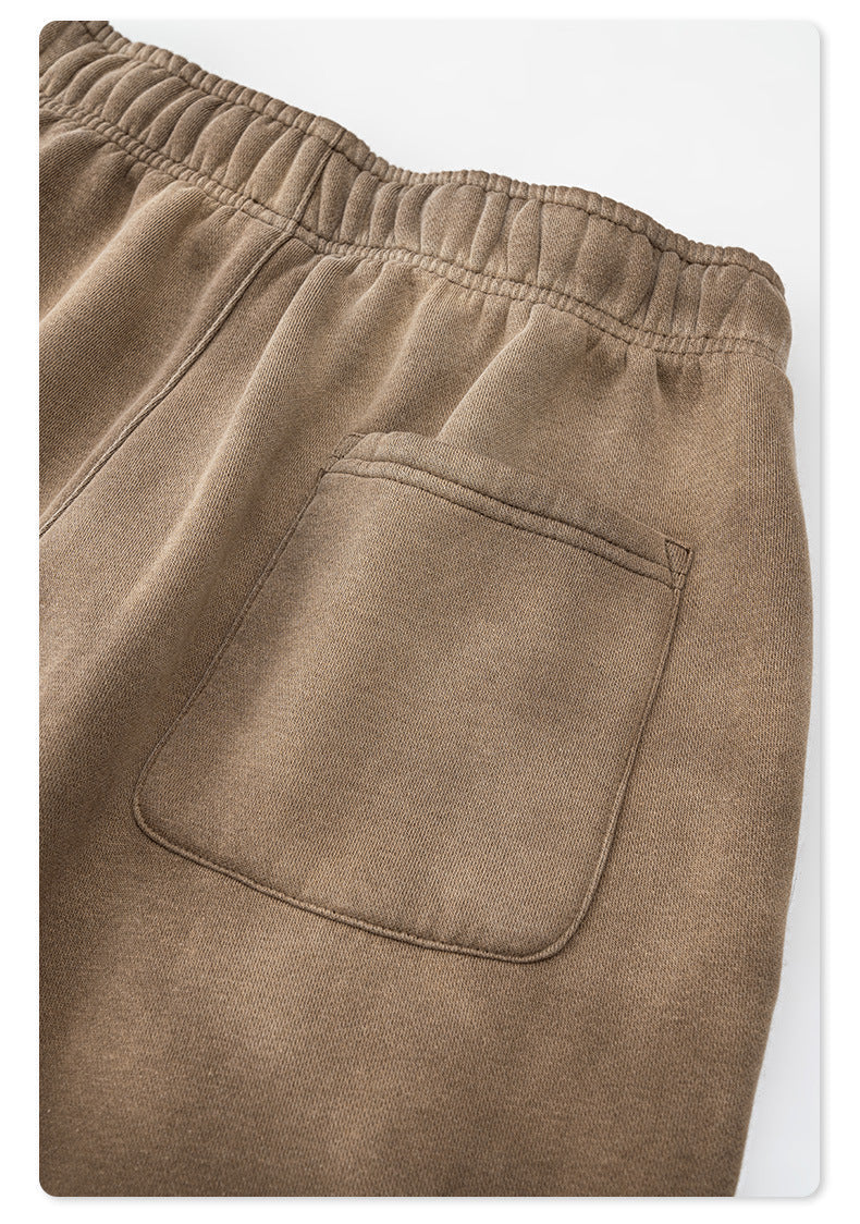 Close-up of taupe sweatpants back pocket detail and elastic waistband against white background